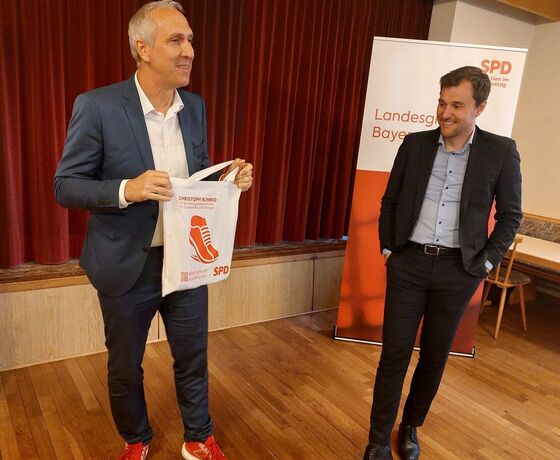 MdB Christoph Schmid überreicht MdB Johannes Schätzl einen Jutebeutel mit dem Logo "Läuft für Sie"